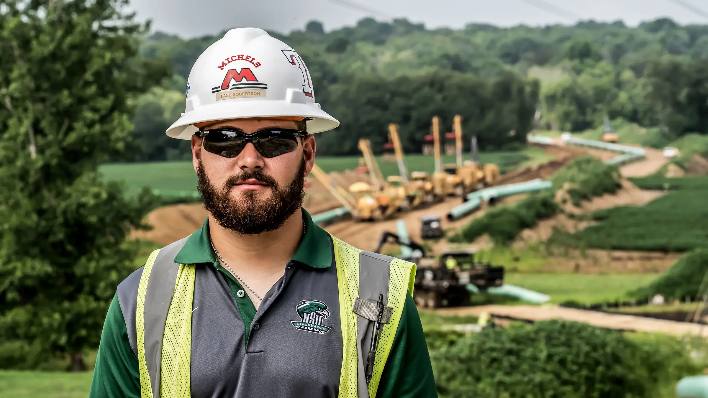 A Michels crew member wearing safety glasses and a hardhat stands near a major pipeline project.