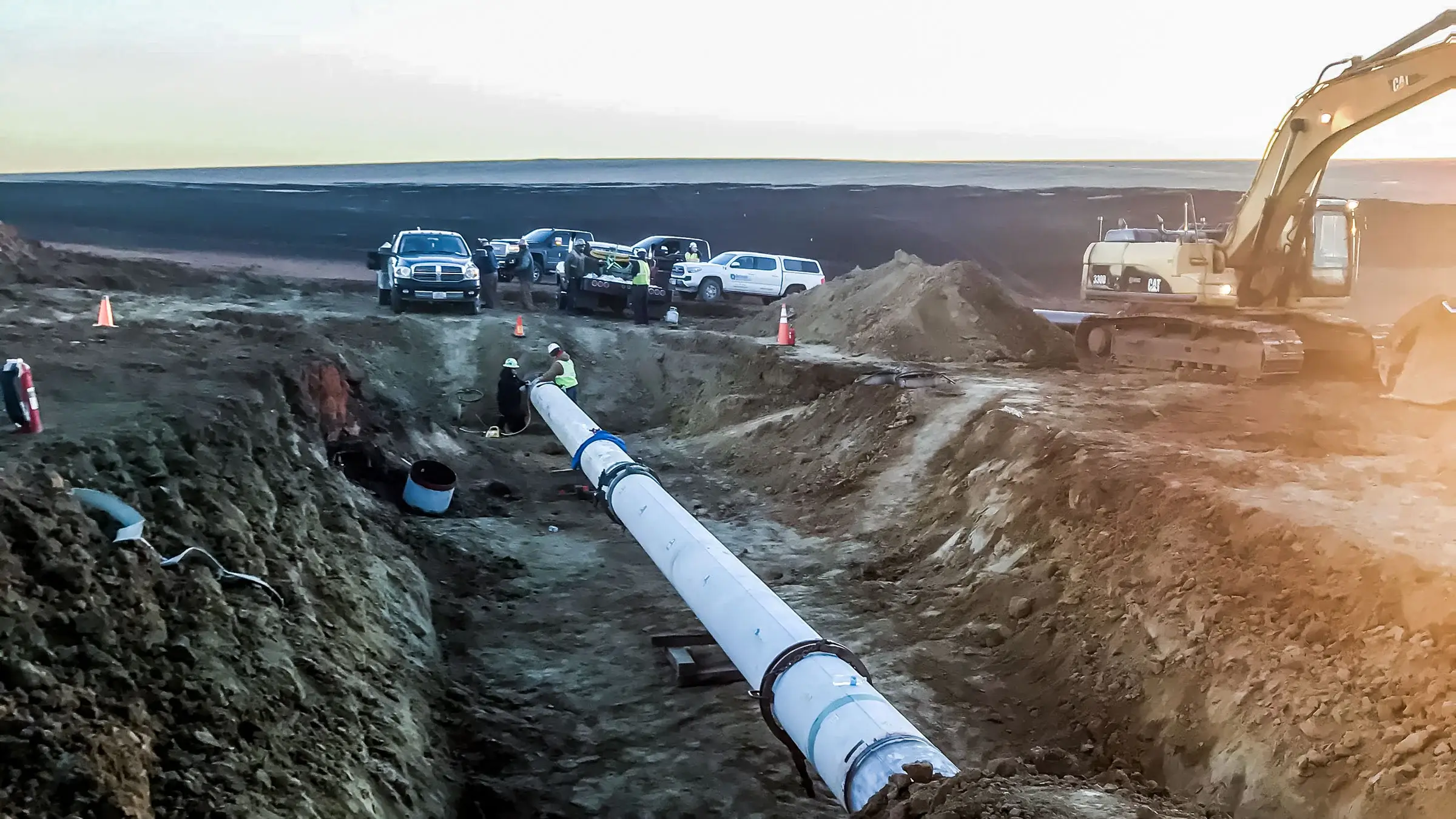 Two crew members fabricate a part of a pipeline