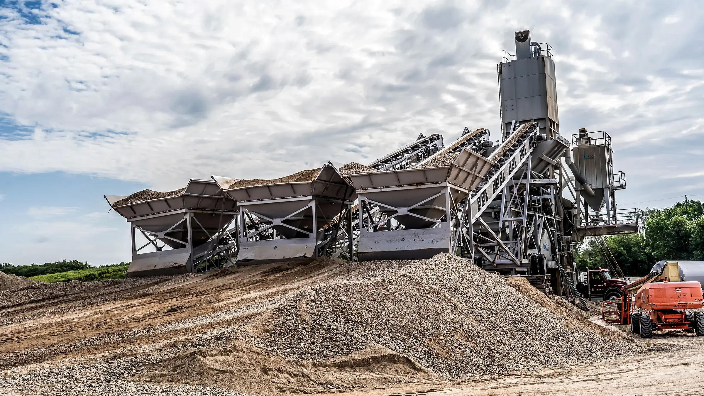 Various aggregates being sorted at a batch plant through large machinery.