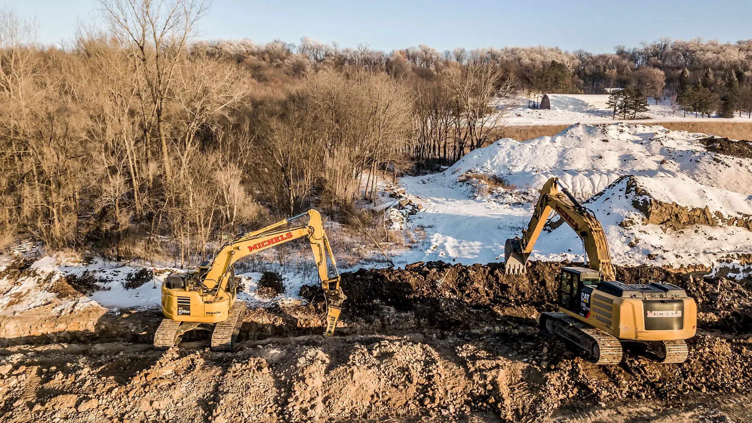 Two excavators work near a trench.