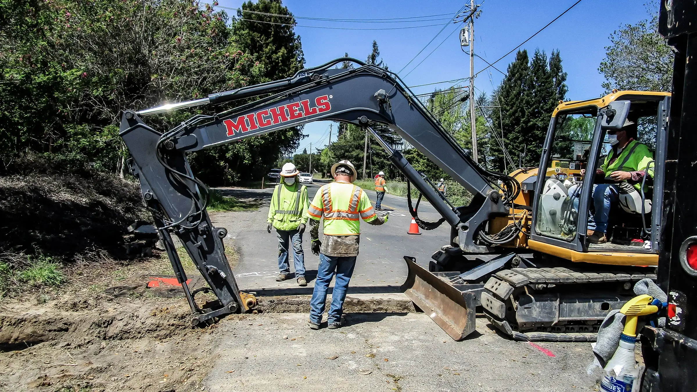 Workers overlook as excavator prepares hole at jobsite