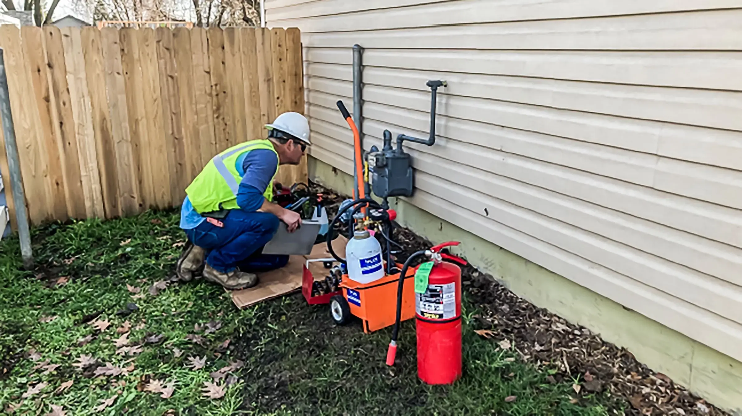 A worker inspects a utility meter on the side of a home