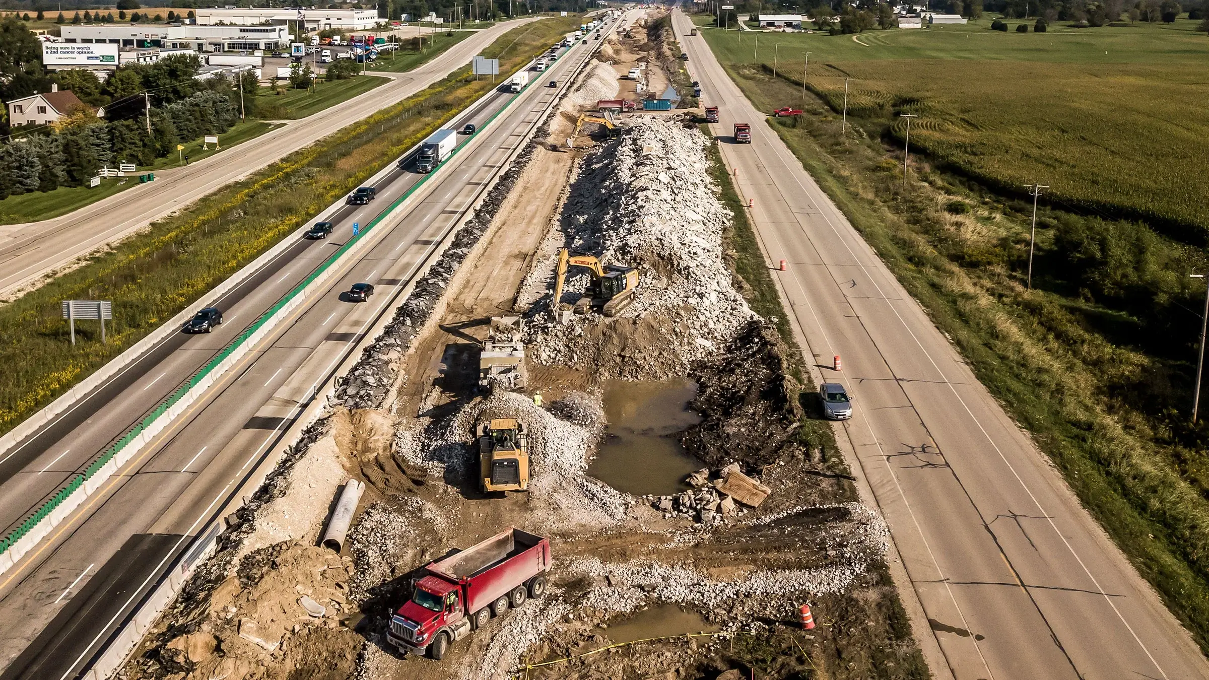 A recycle crushing plant in between roads being utilized by several large pieces of Michels equipment