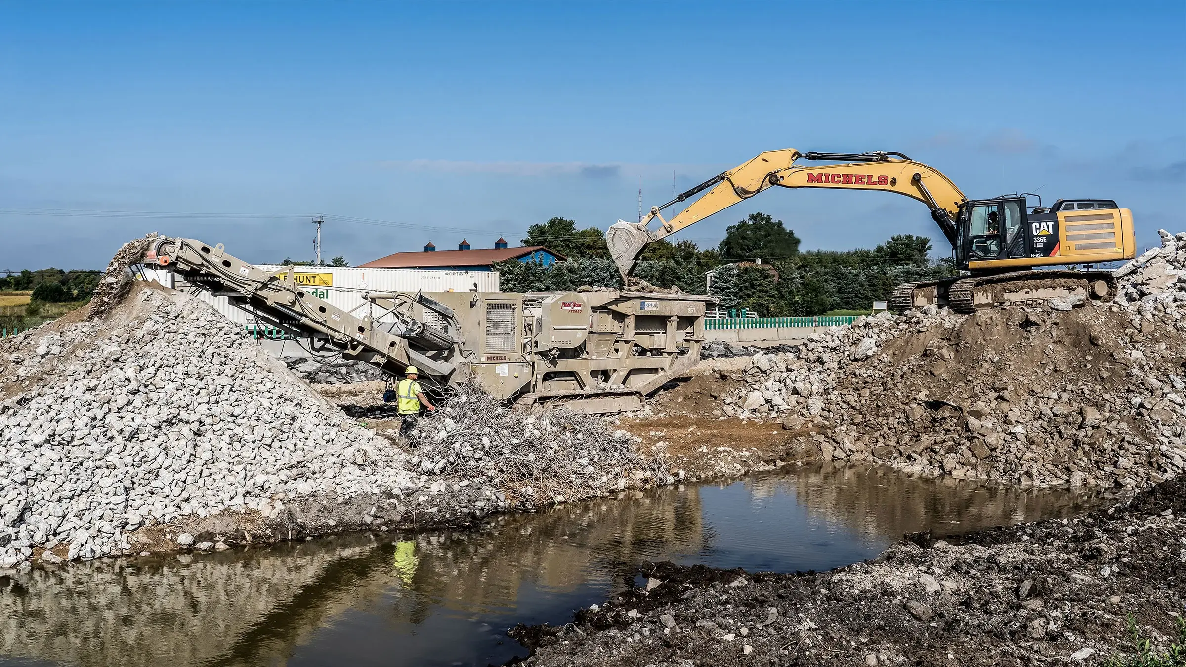 Aggregates being sorted by excavator at a batch plant.