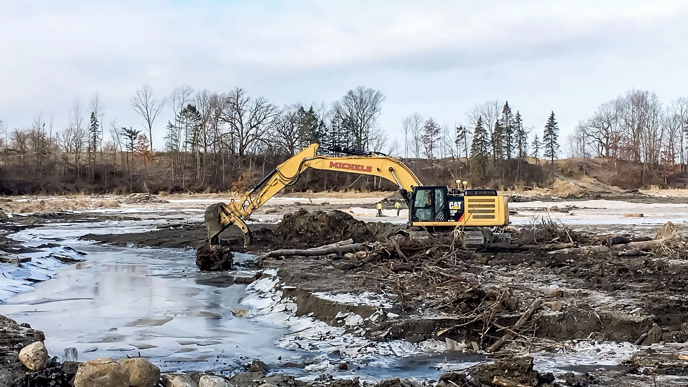 Excavator clears mud from waterway in the winter