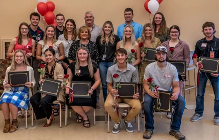 Group of scholarship award winners stand for a photo holding their scholarships with some of the Michels family