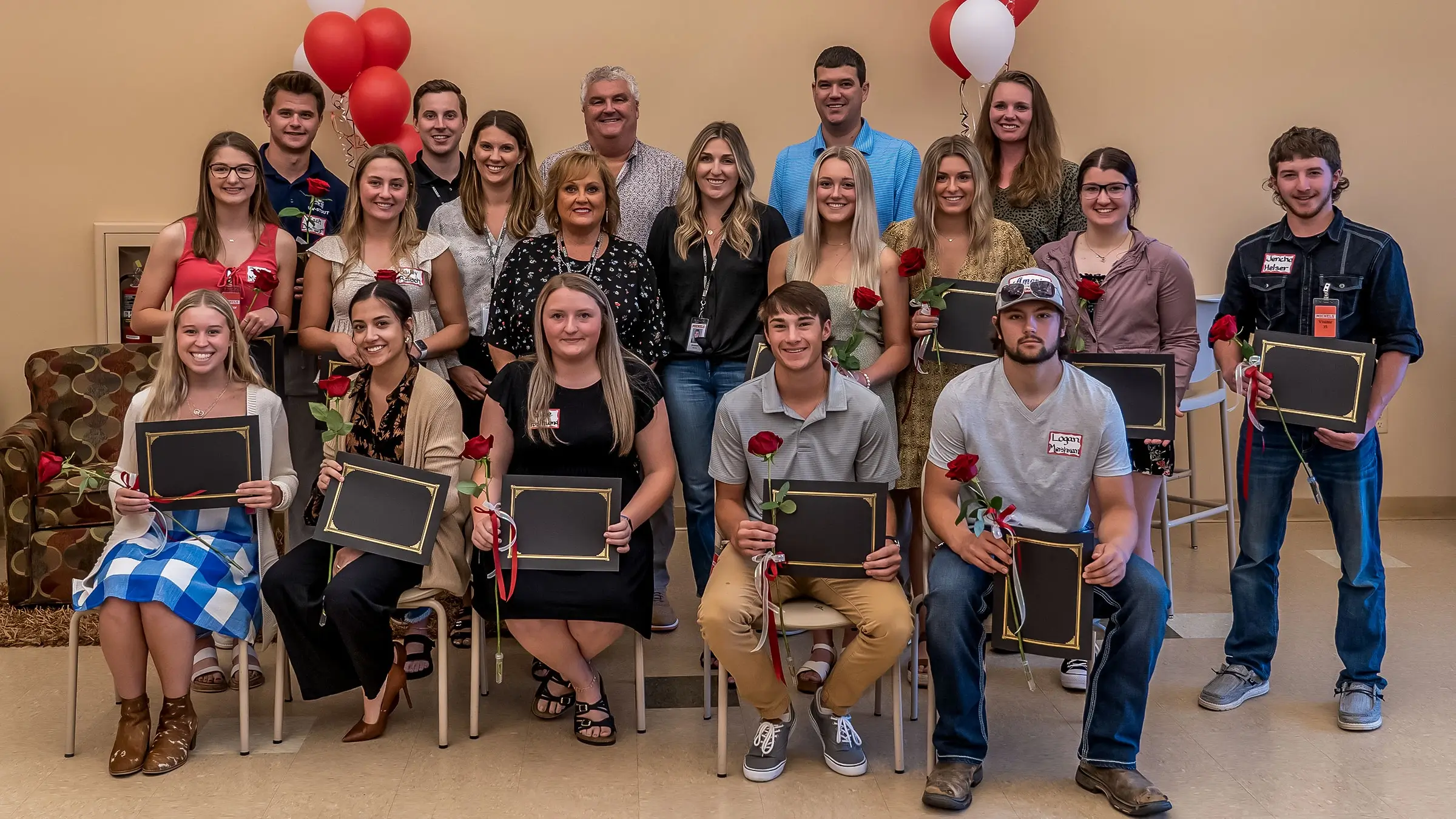 Group of scholarship award winners stand for a photo holding their scholarships with some of the Michels family