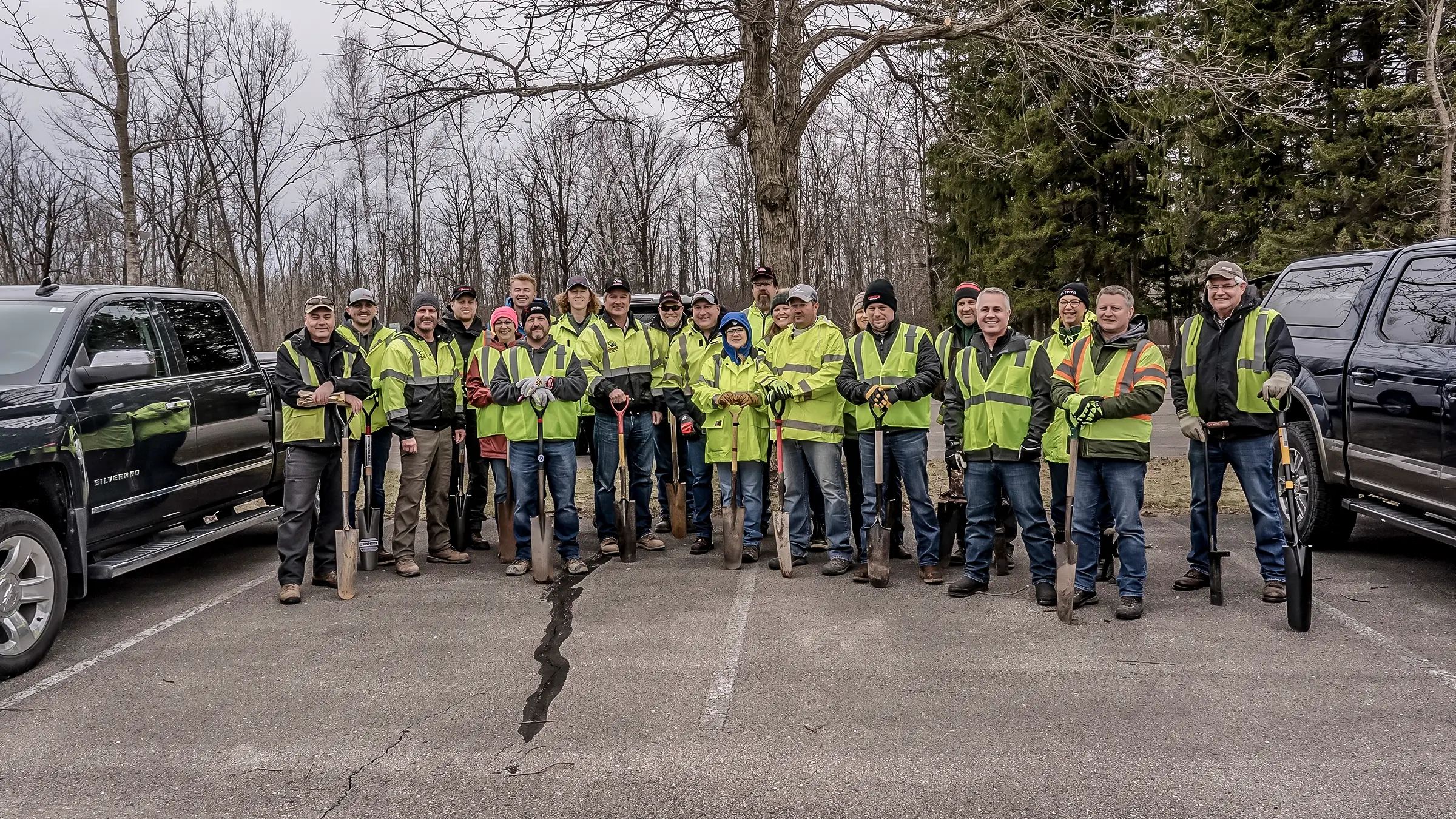 Group of workers after planting trees with their shovels.