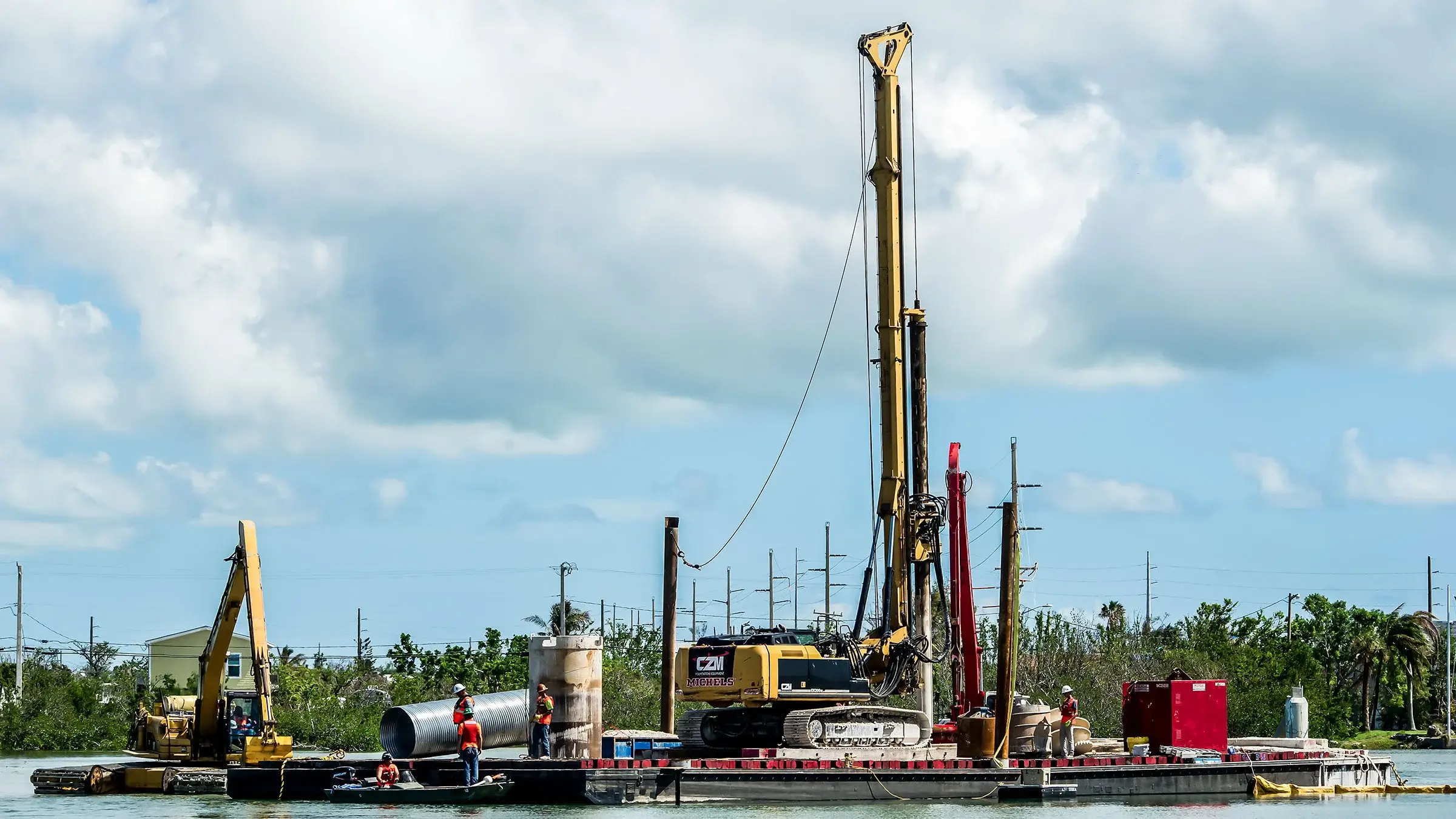 A large drill rig operates on a water barge.