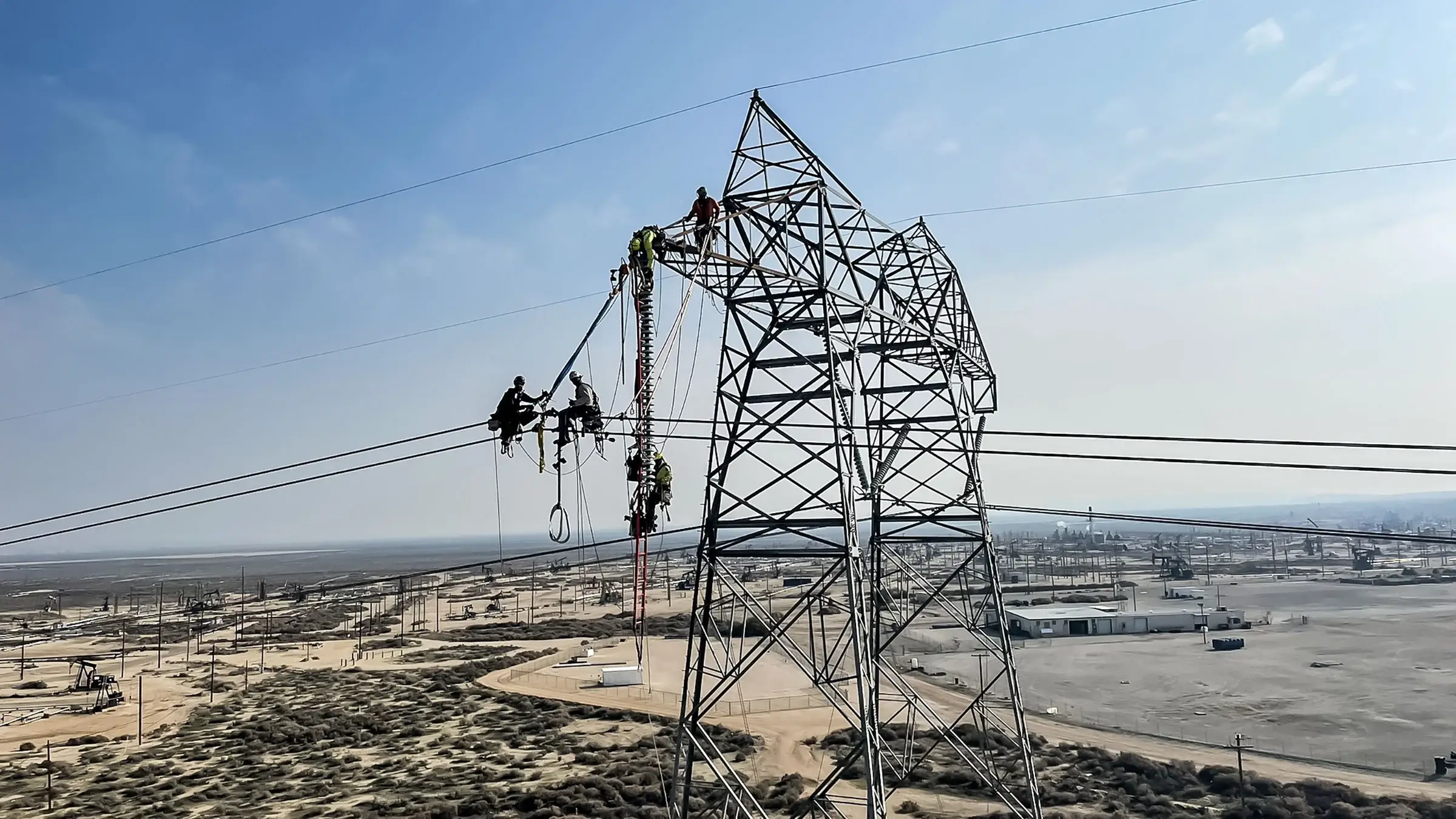 A Michels Pacific Energy crew operates at the top of a power line structure