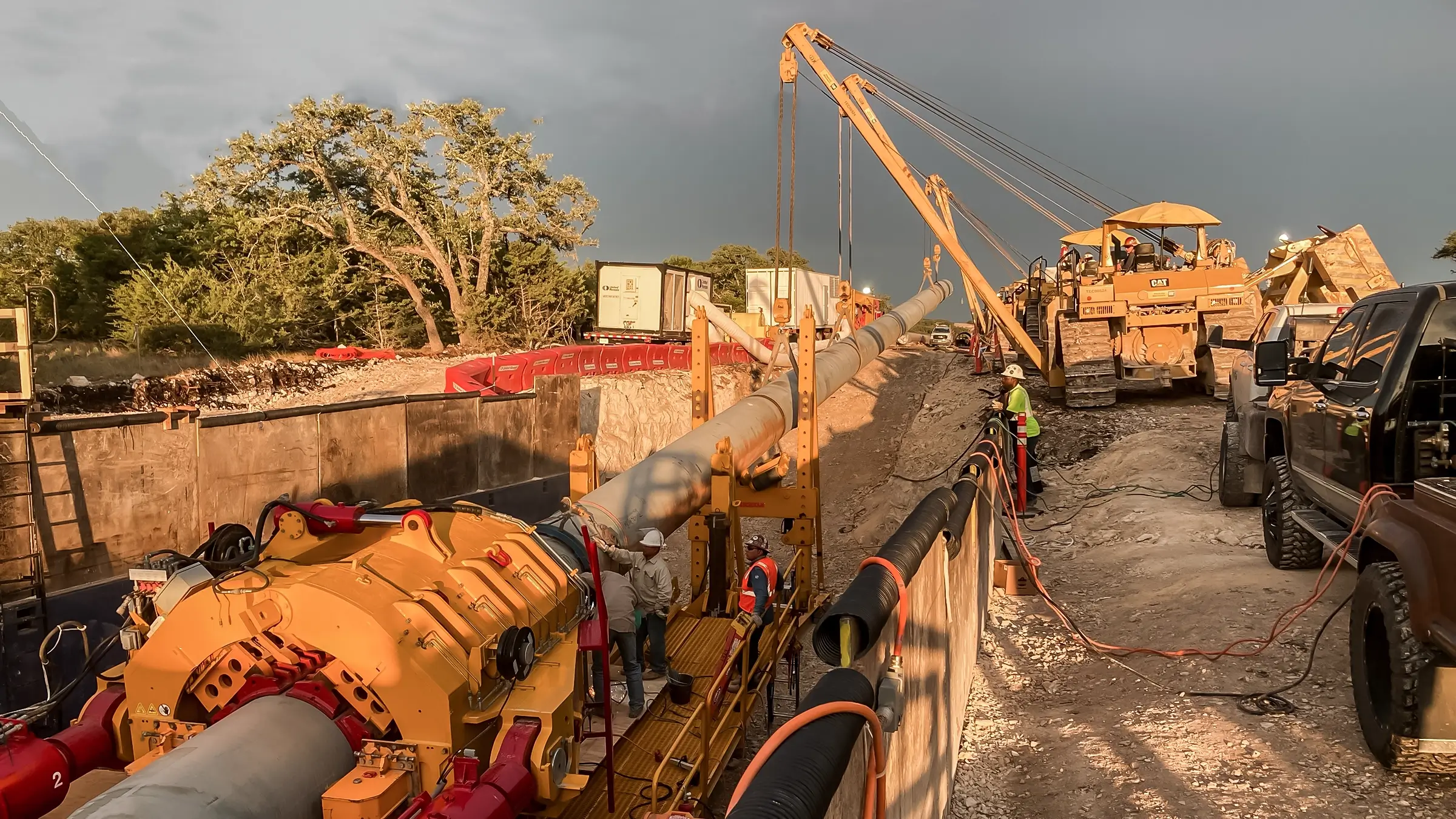 Several pipelayer machines assist in a Direct Pipe job on a cloudy day