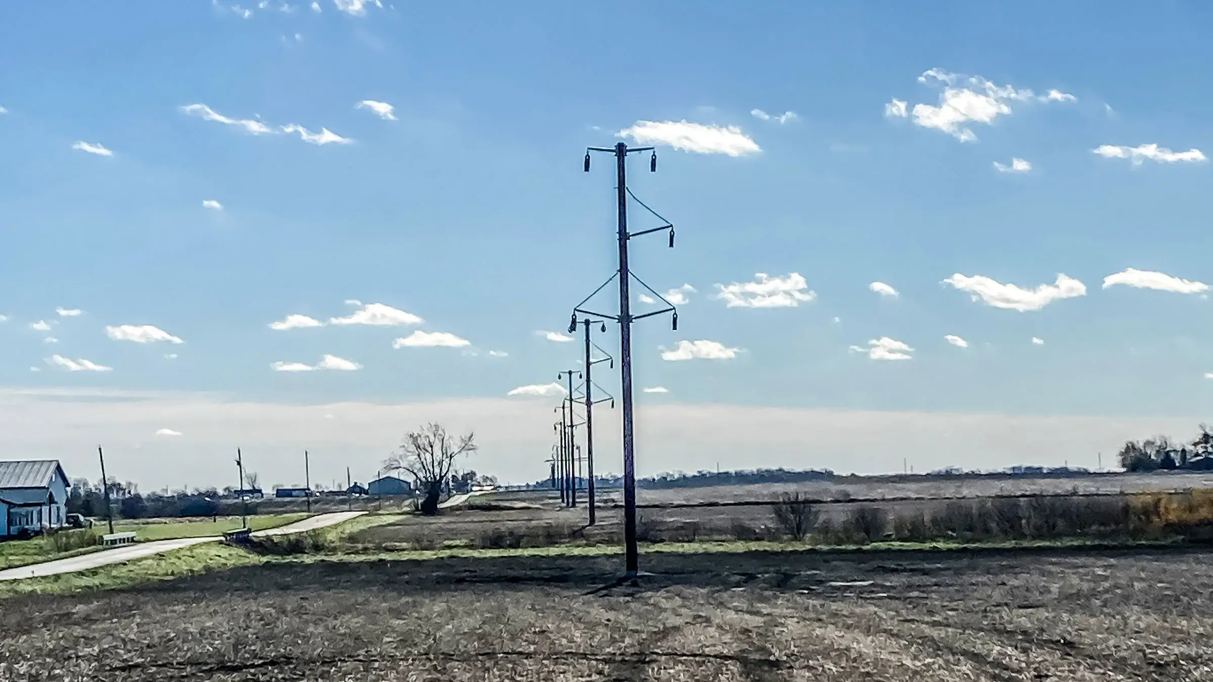 A series of power line poles run through farmland
