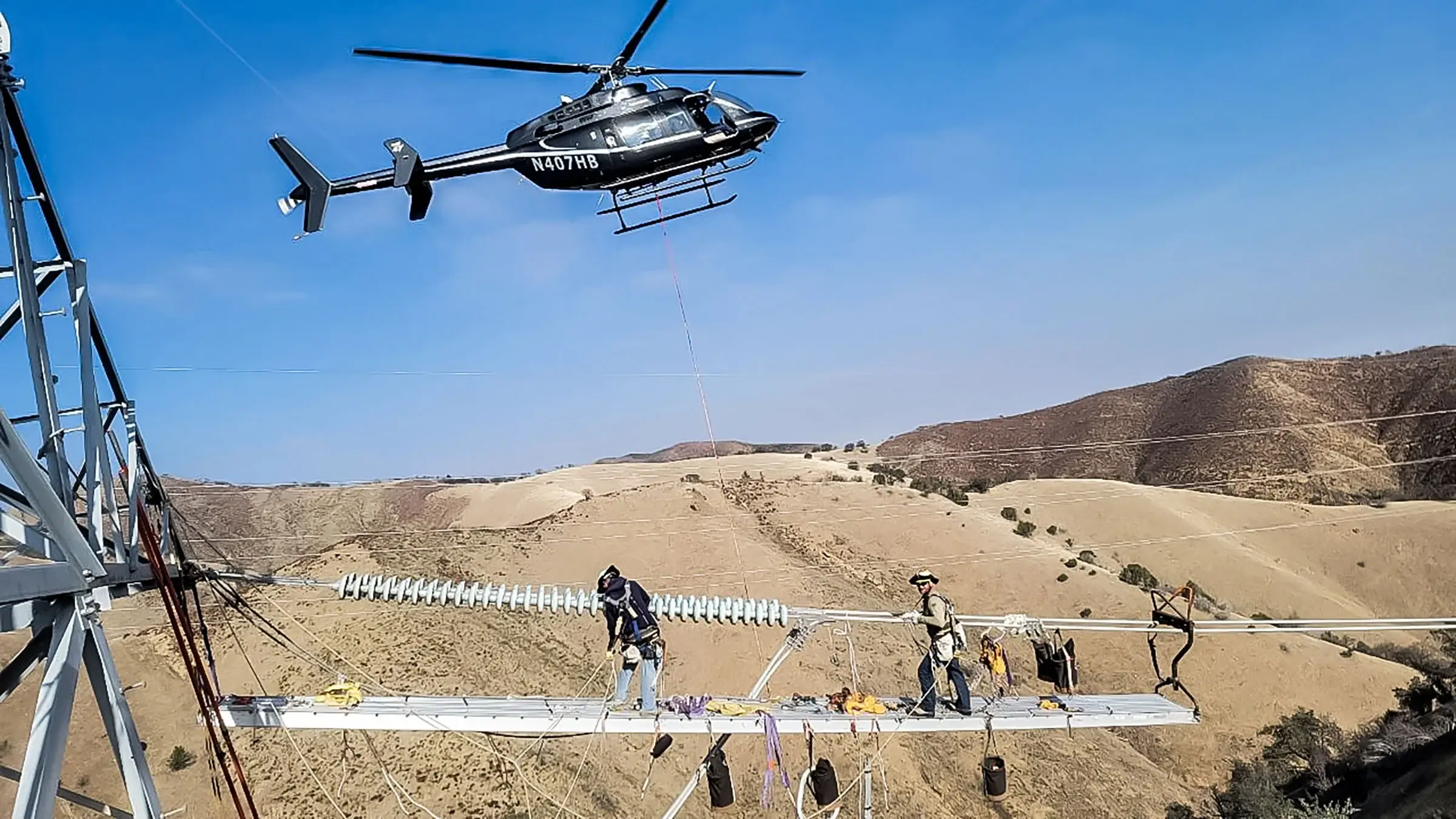 Michels Power Inc helicopter helping workers install insulators above a canyon.