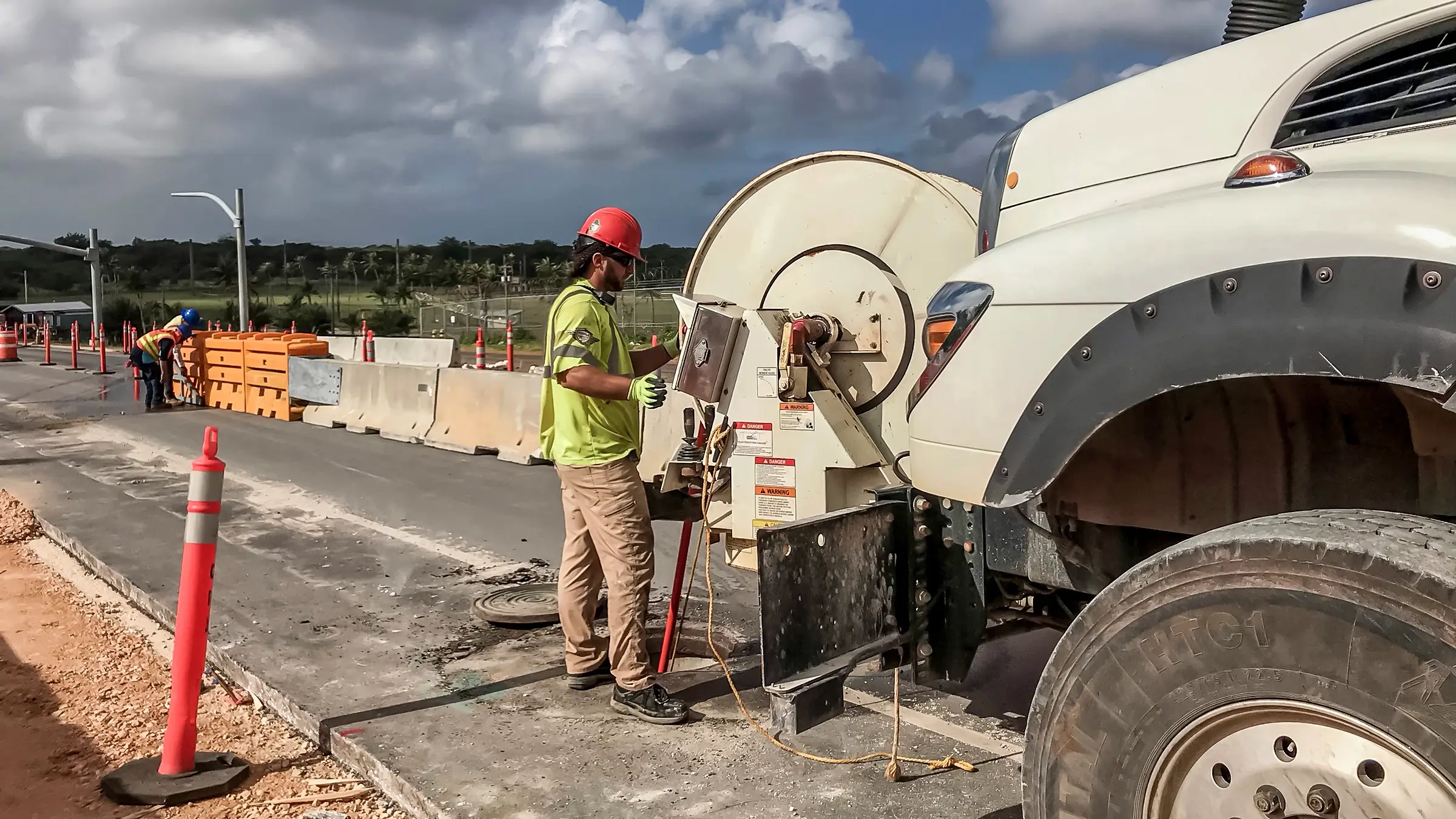 A crew member works on a roadside by a truck in Guam