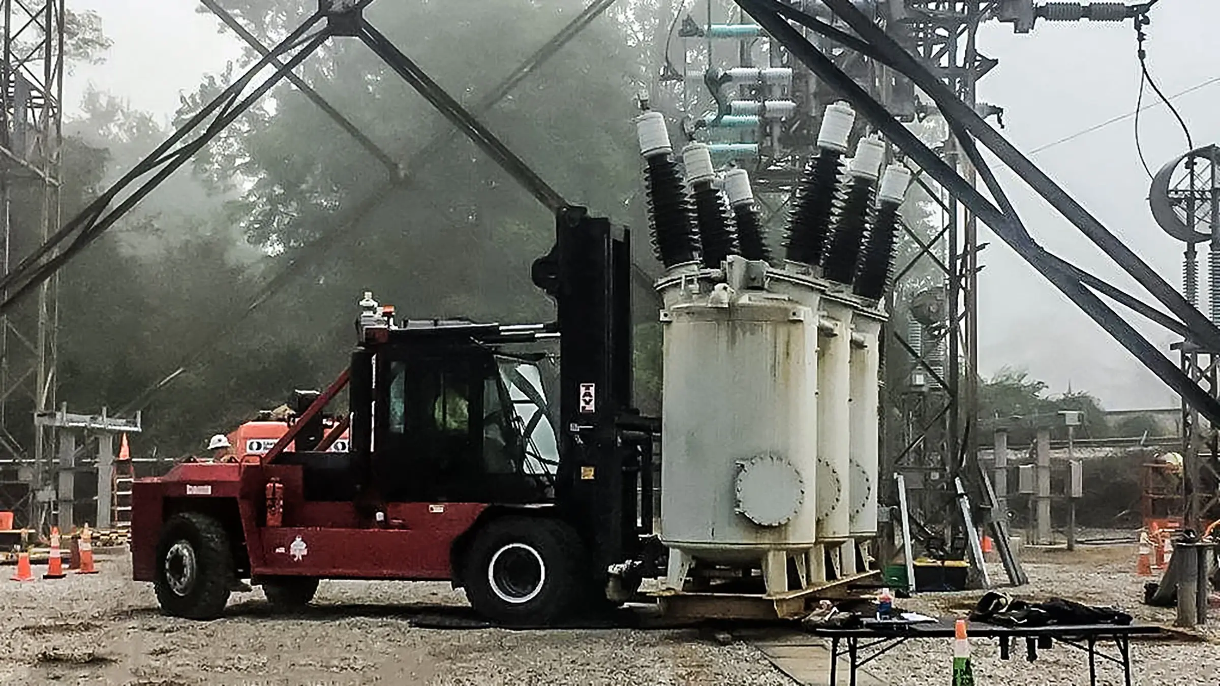 A forklift carries substation equipment on a jobsite