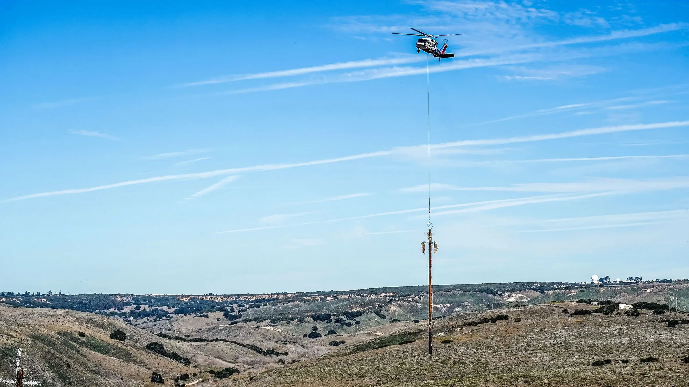 A large helicopter assists in the replacement of a large power pole