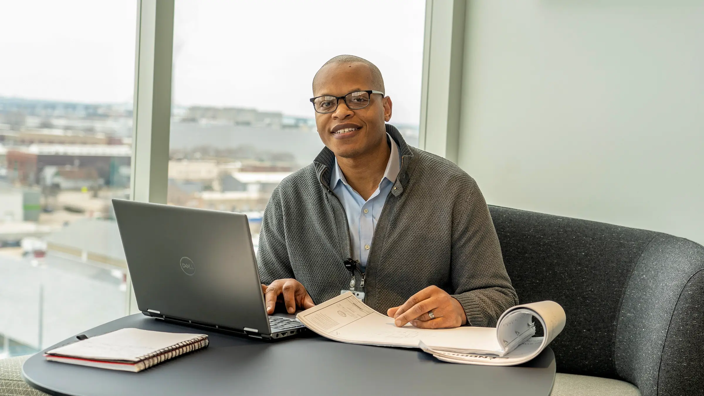 Man smiles while sitting at a desk at the R1VER office.