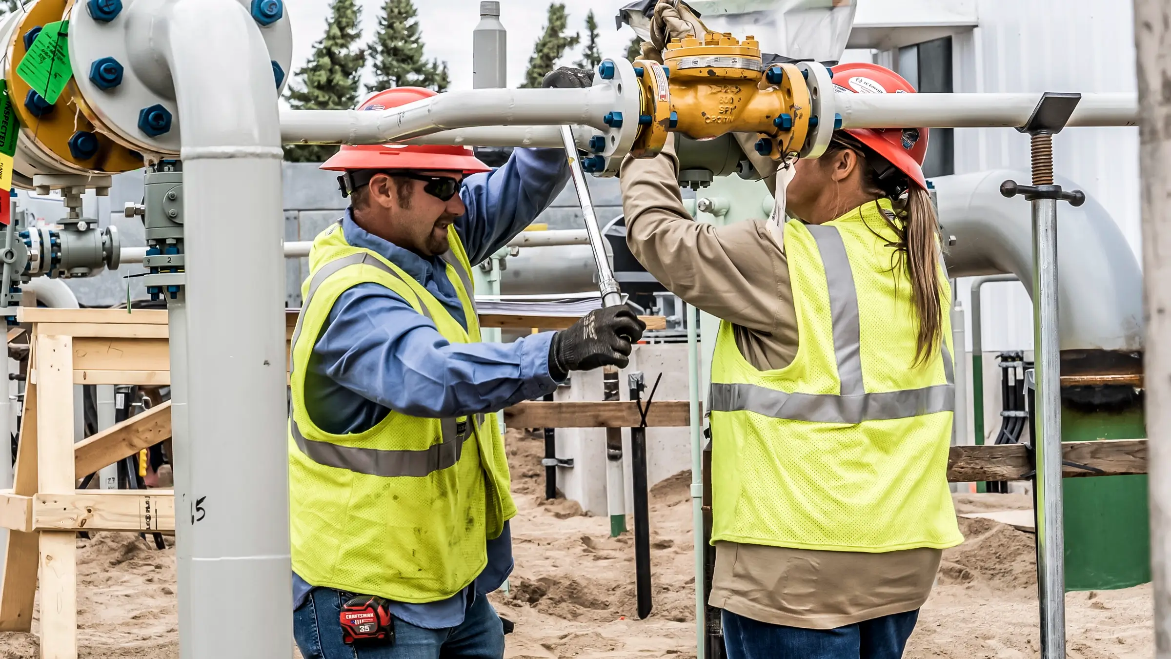 A worker uses a tool to tighten a value in a natural gas compressor station