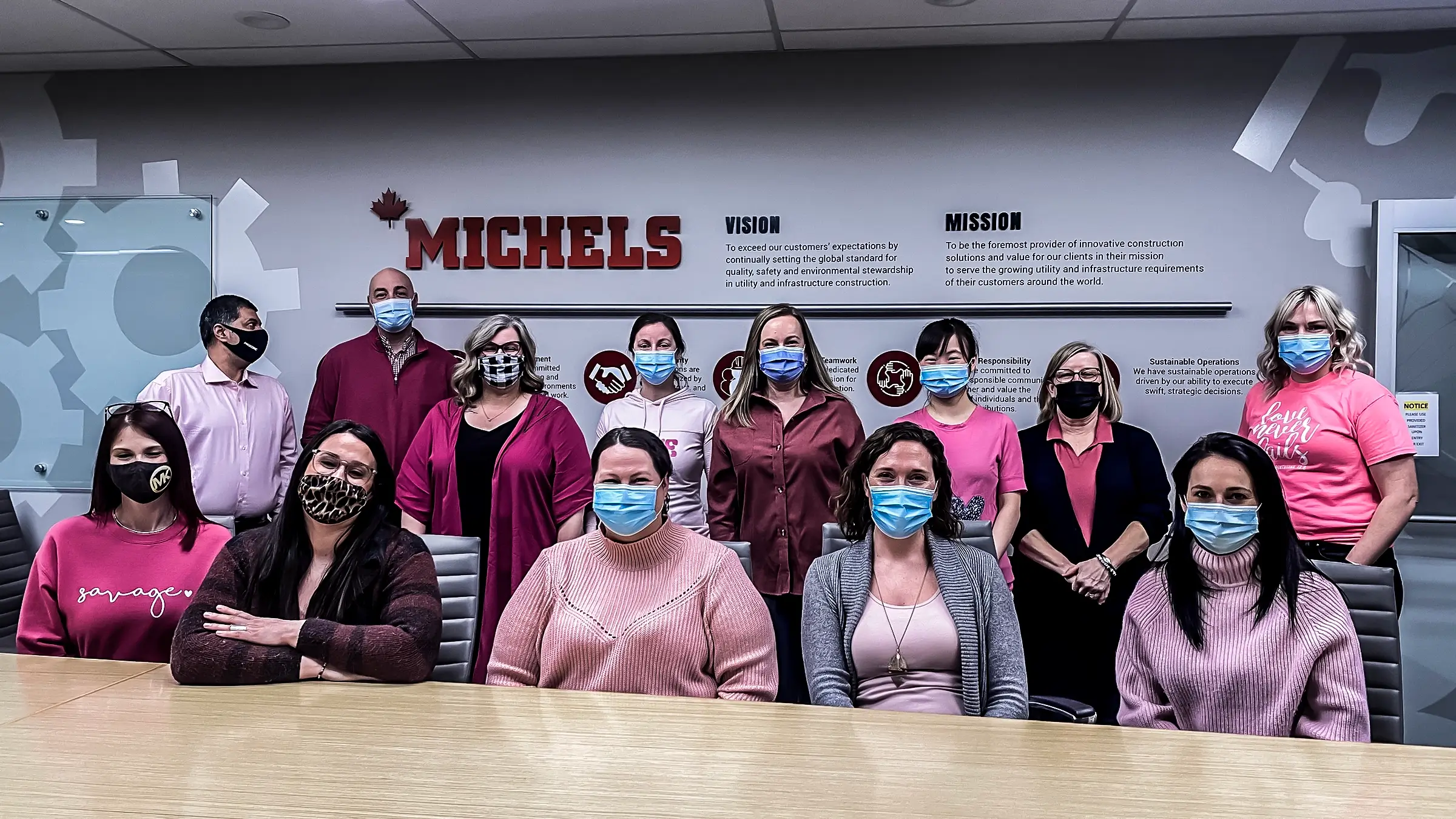 Team of Michels employees all wearing pink shirts in office
