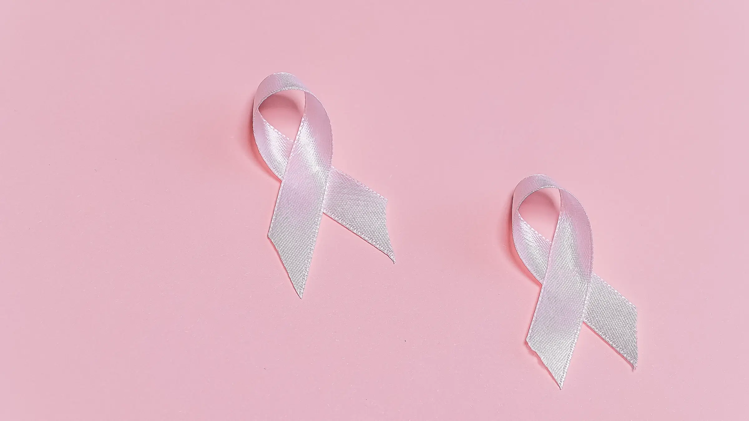 Two pink breast cancer awareness ribbons on pink background