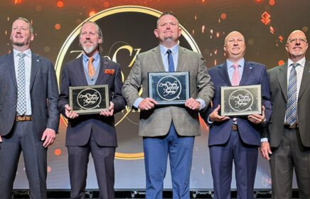 Five men stand on a stage with ZISA construction awards.