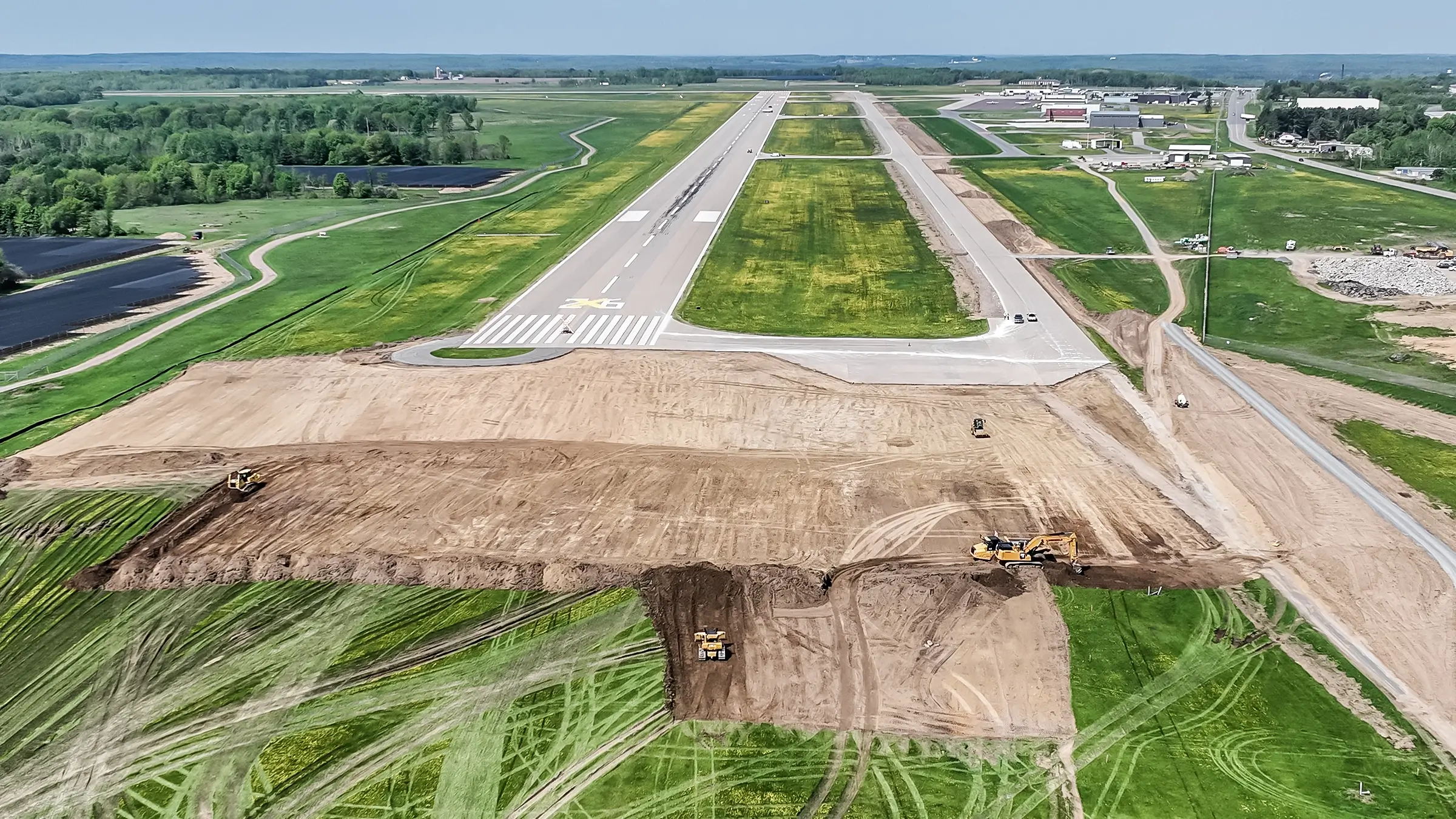 Large area of dirt is cleared for runway extension.