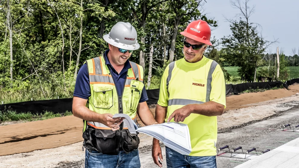Two Road & Stone paving crew members discuss project plans.