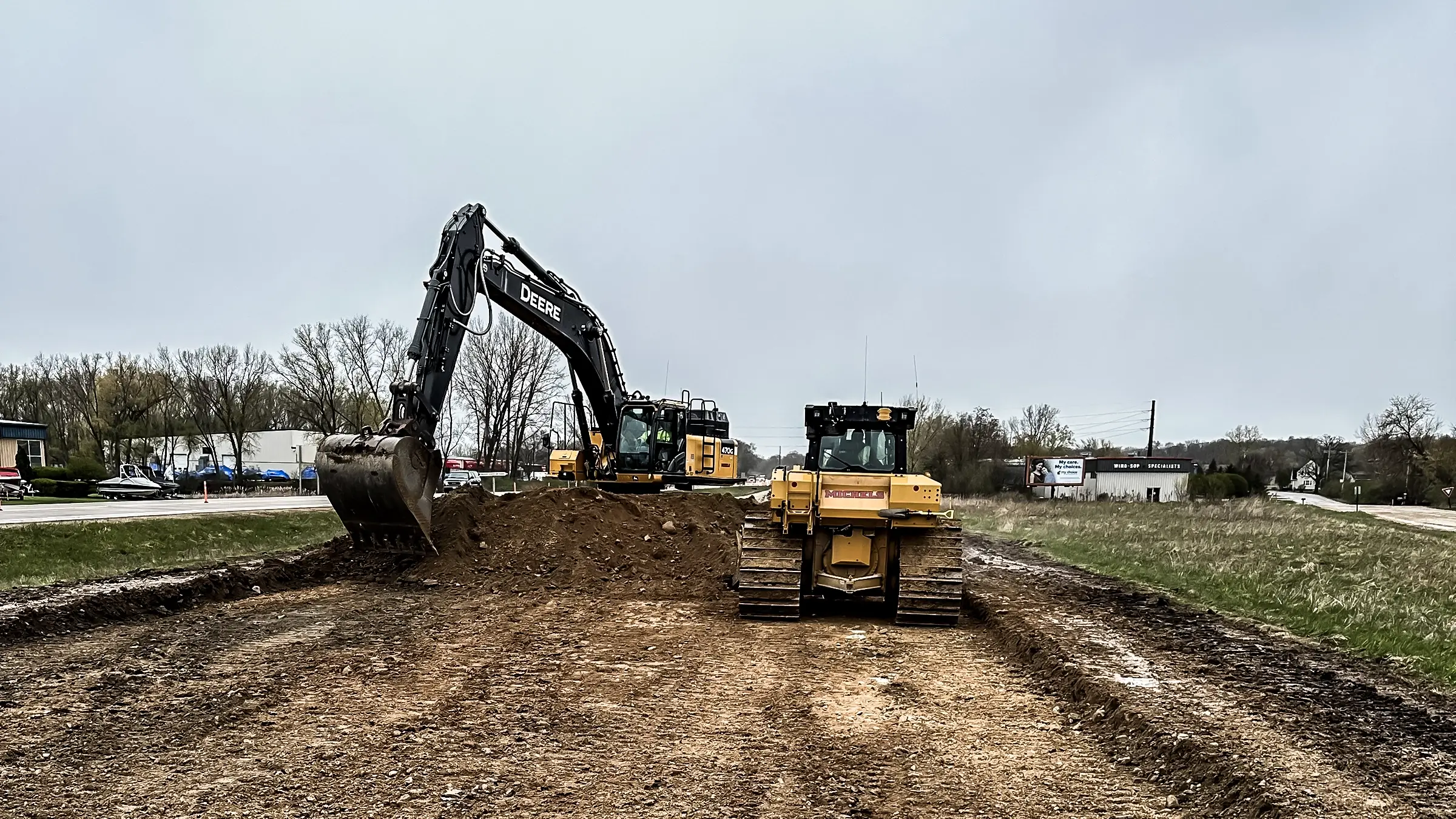 A bulldozer and backhoe layout an excavated road.