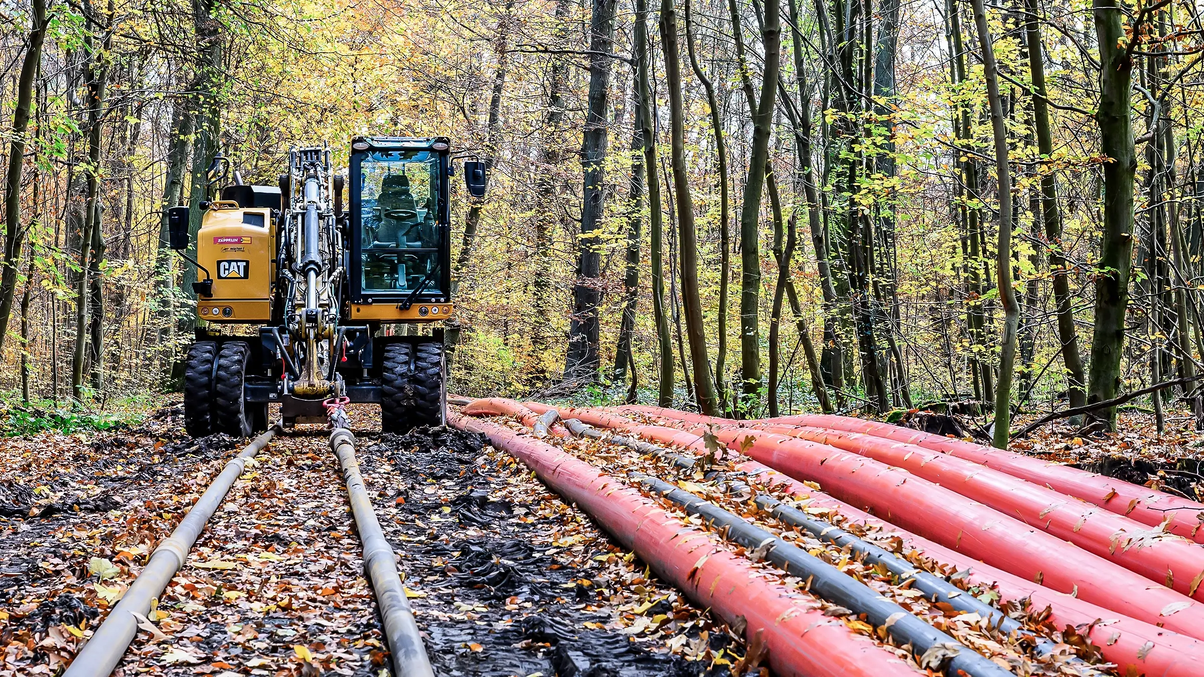 Equipment pulling cables through a rural wooded area.